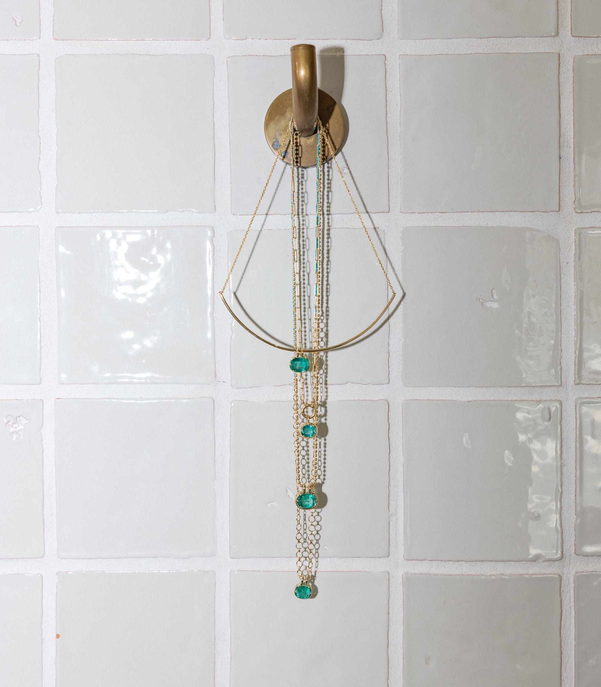 14k Solid Gold Fine Jewelry Emerald Pendants On Gold Chain Hanging From Bathroom Hook Styled Lifestyle Shot