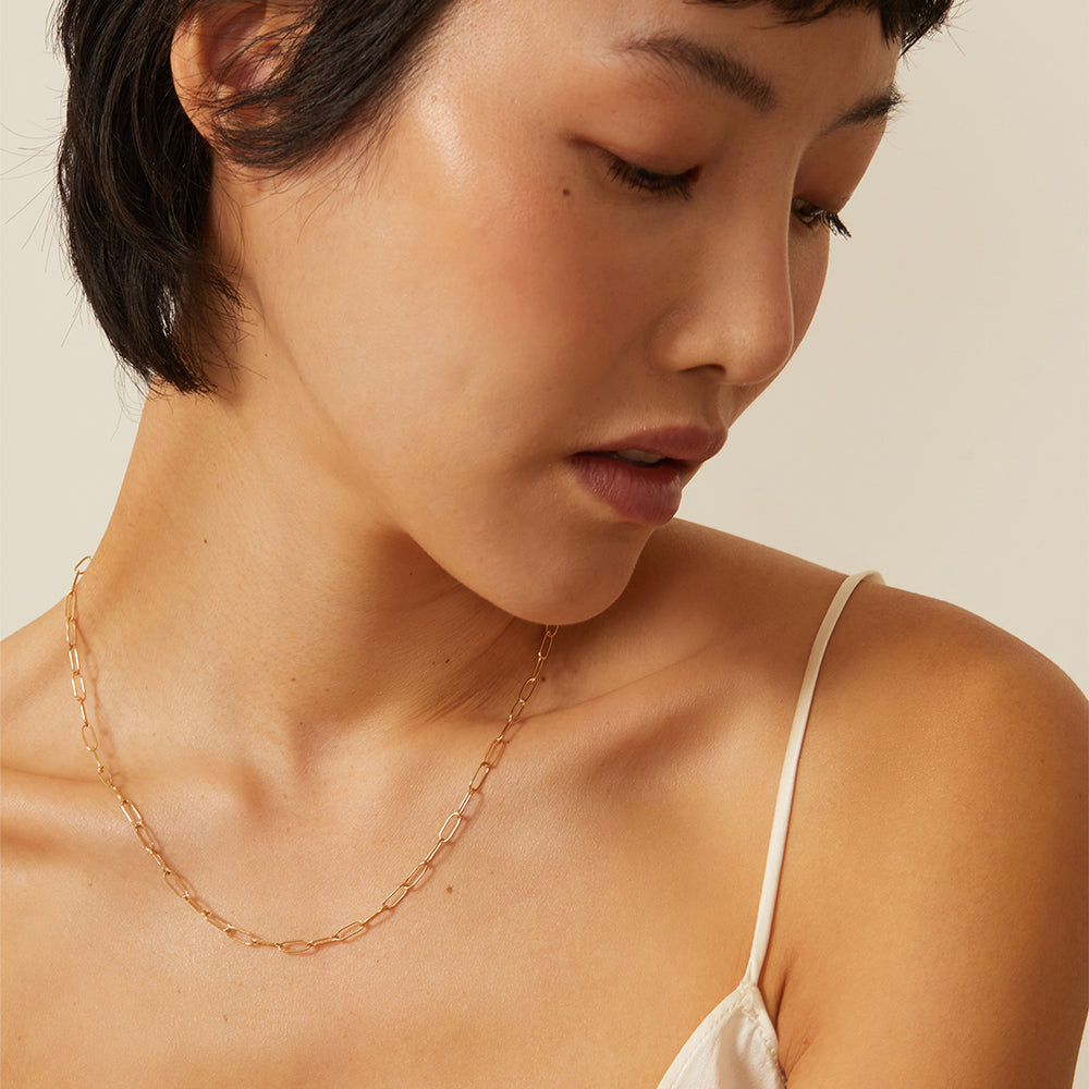 The Trendy CN-C7 gold necklace with warm light, fine oval links chain close-up on model