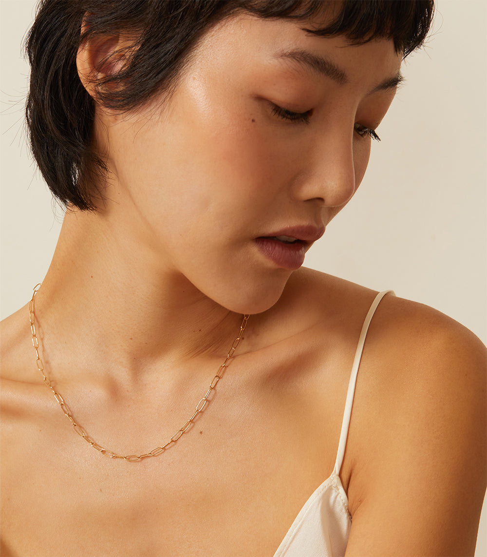 The Trendy CN-C7 gold necklace with warm light, fine oval links chain close-up on model