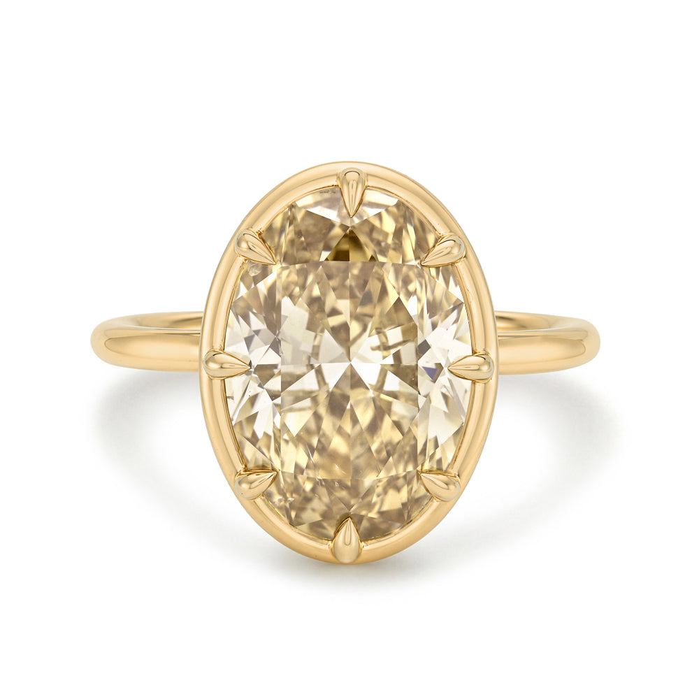 An oval-cut diamond ring in a yellow gold setting, shown against a plain white background.
