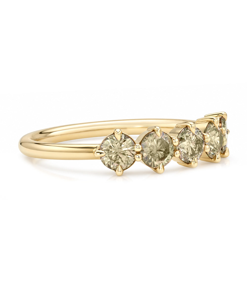 A yellow gold ring featuring three round-cut pale greenish-yellow gemstones in a row, set against a clean white background.