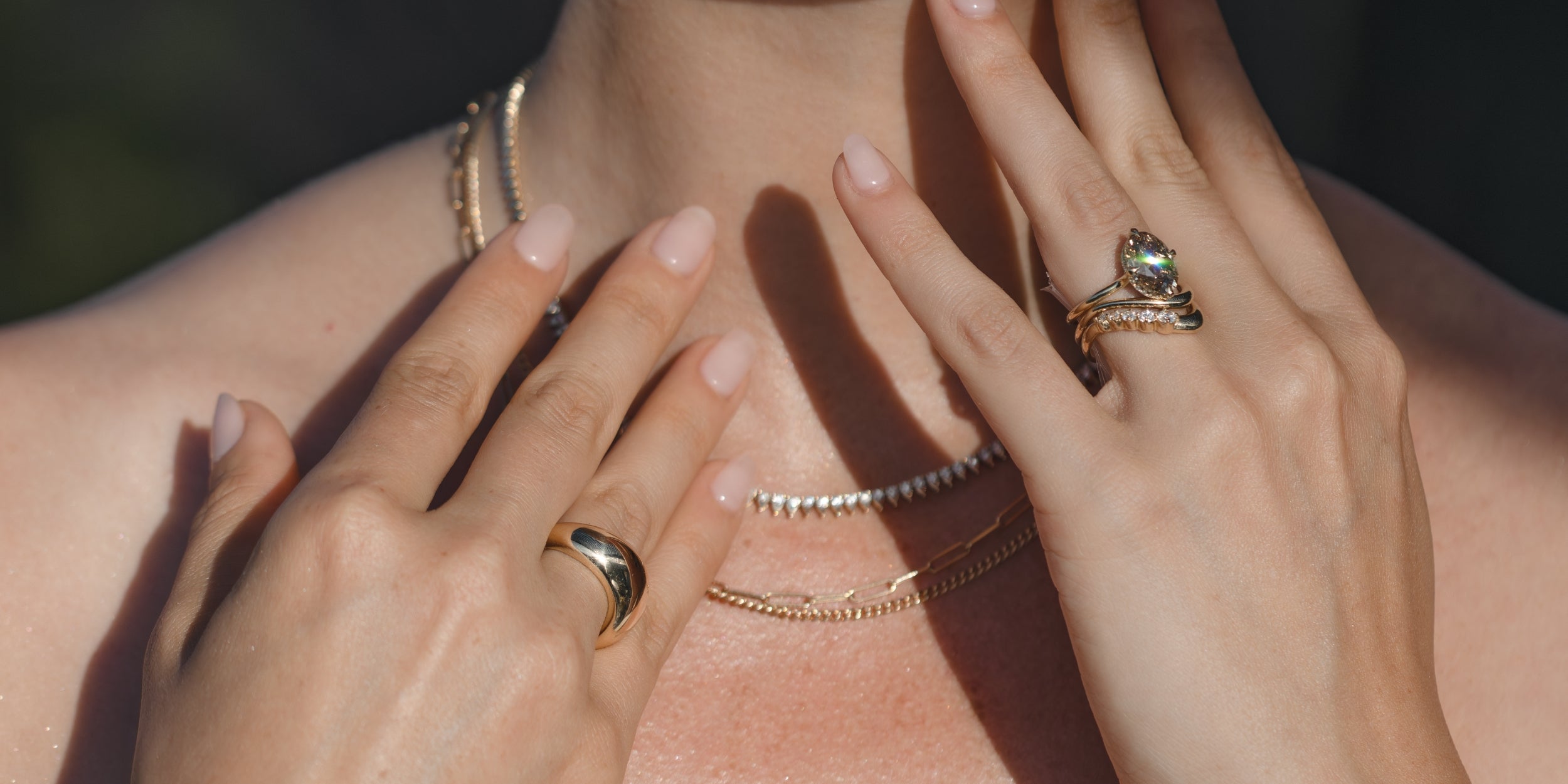 Hands wearing a unique engagement ring—an asymmetrical setting with a round diamond sparkle on one finger