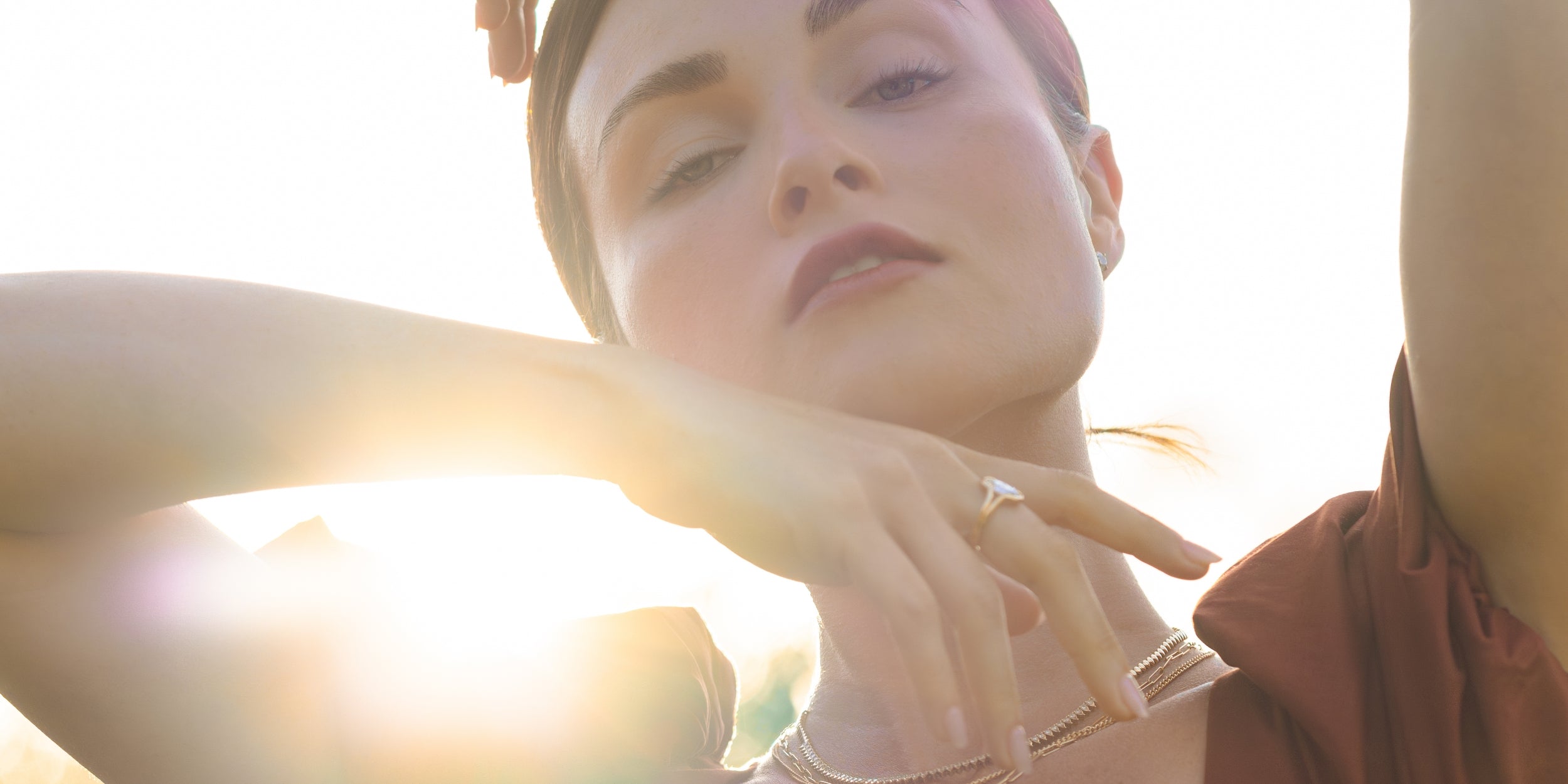 Understated unique engagement ring on a woman’s hand in bright sunlight, close-up portrait with soft glow