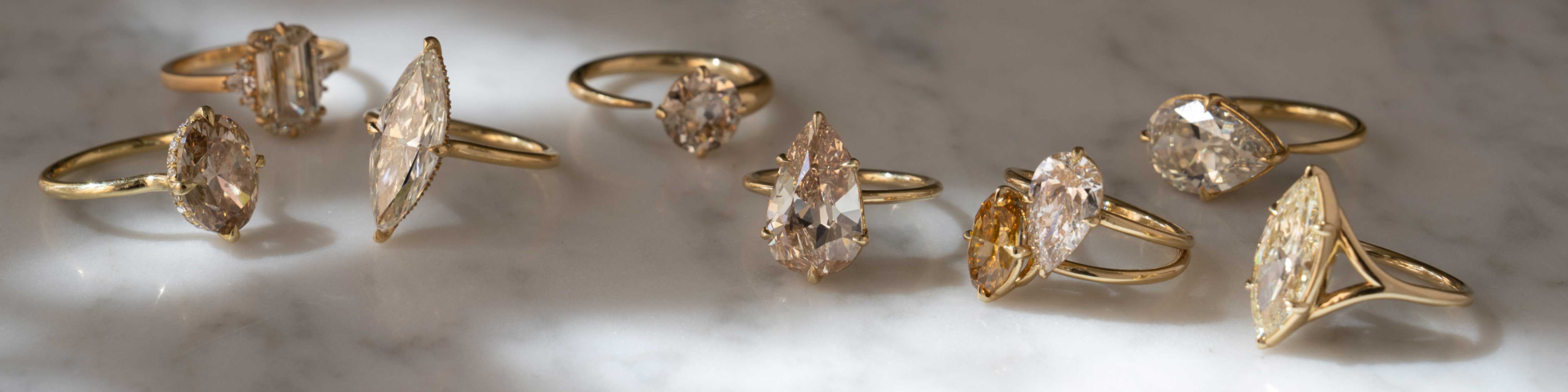 Unique engagement ring set with gold bands and clear marquise-cut stones on a light marble surface