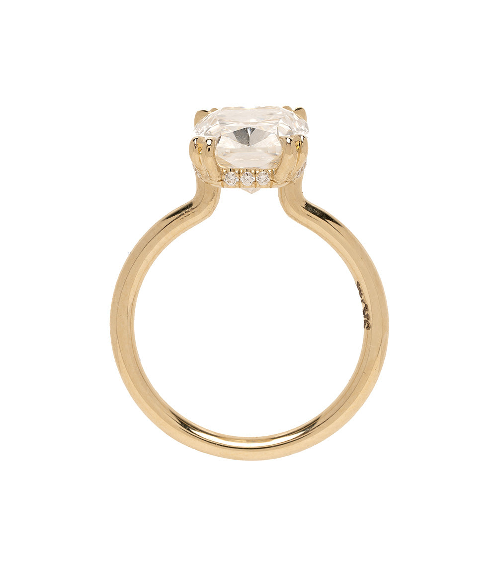 Gold ring with a large diamond and smaller diamonds on the band against a white background