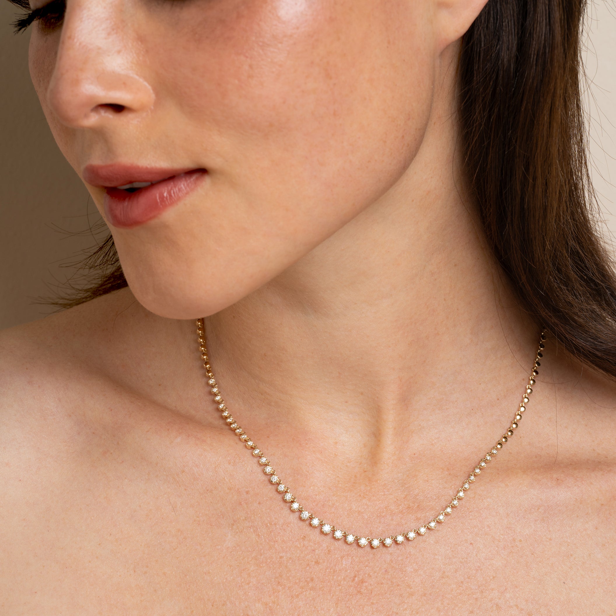 The Brentwood CC-DN11 gold necklace with small sparkling stones rests on bare collarbone