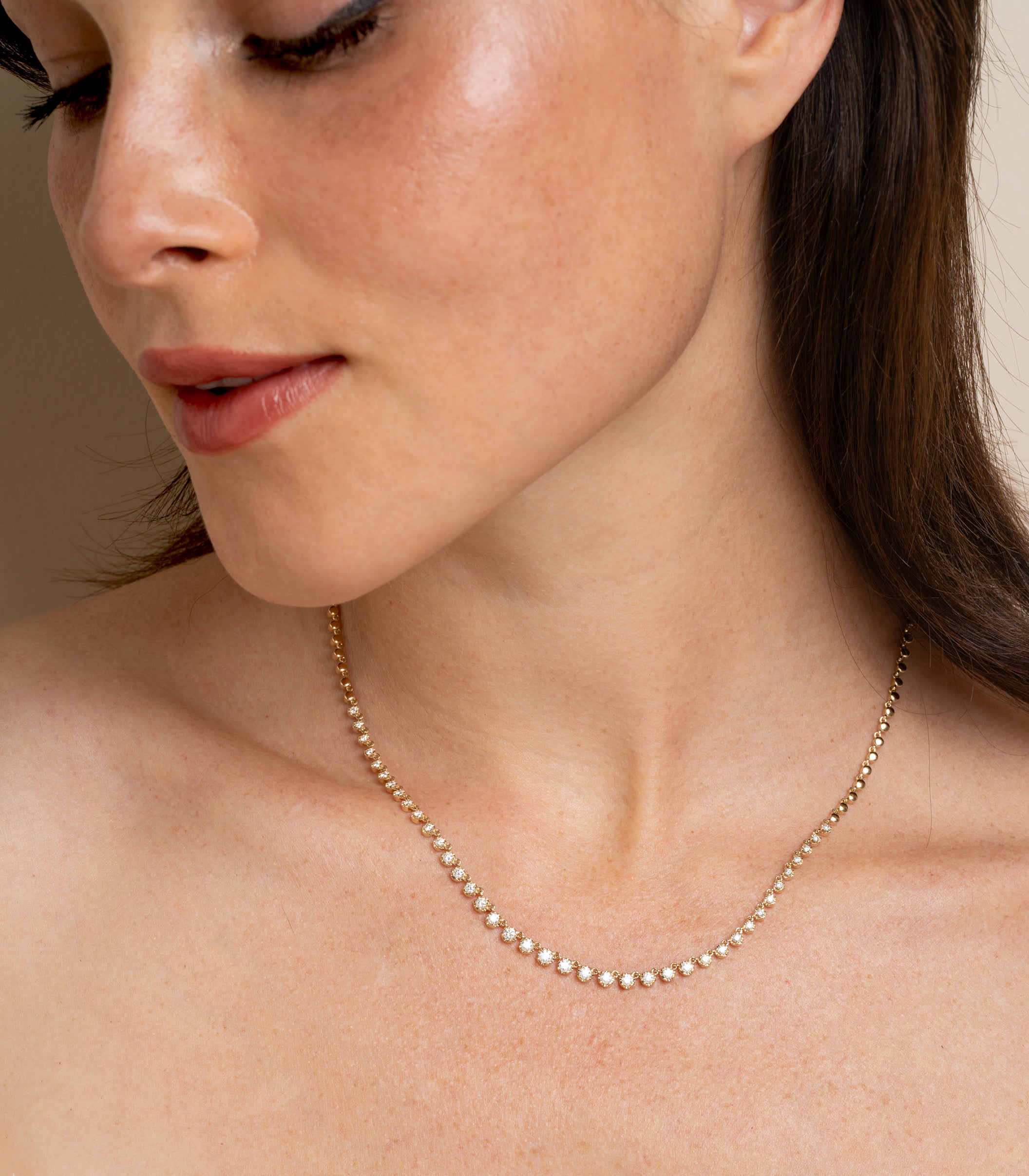 The Brentwood CC-DN11 gold necklace with small sparkling stones rests on bare collarbone