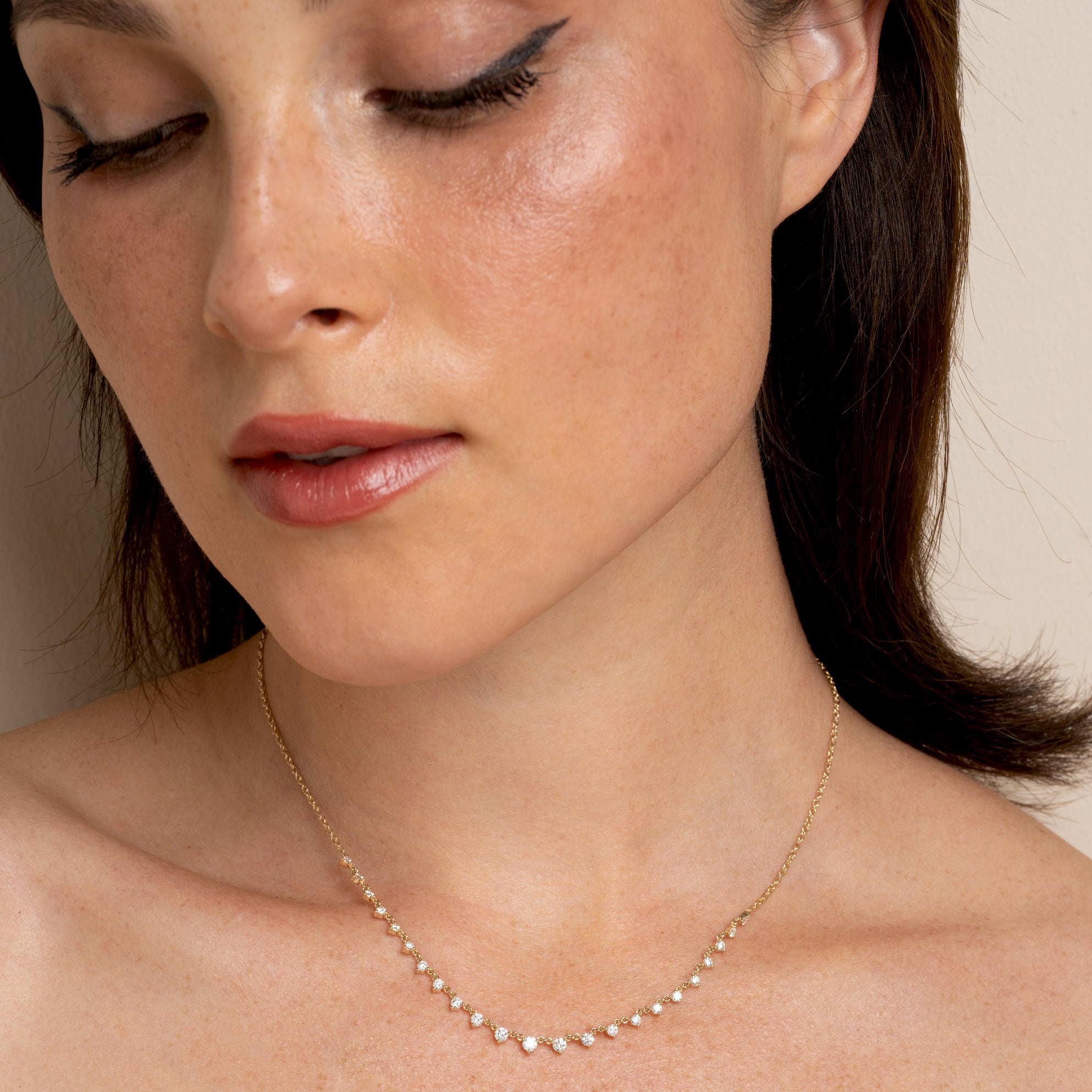The Larchmont CC-DN9 gold necklace on model, delicate chain with small gemstone-like stones in soft light