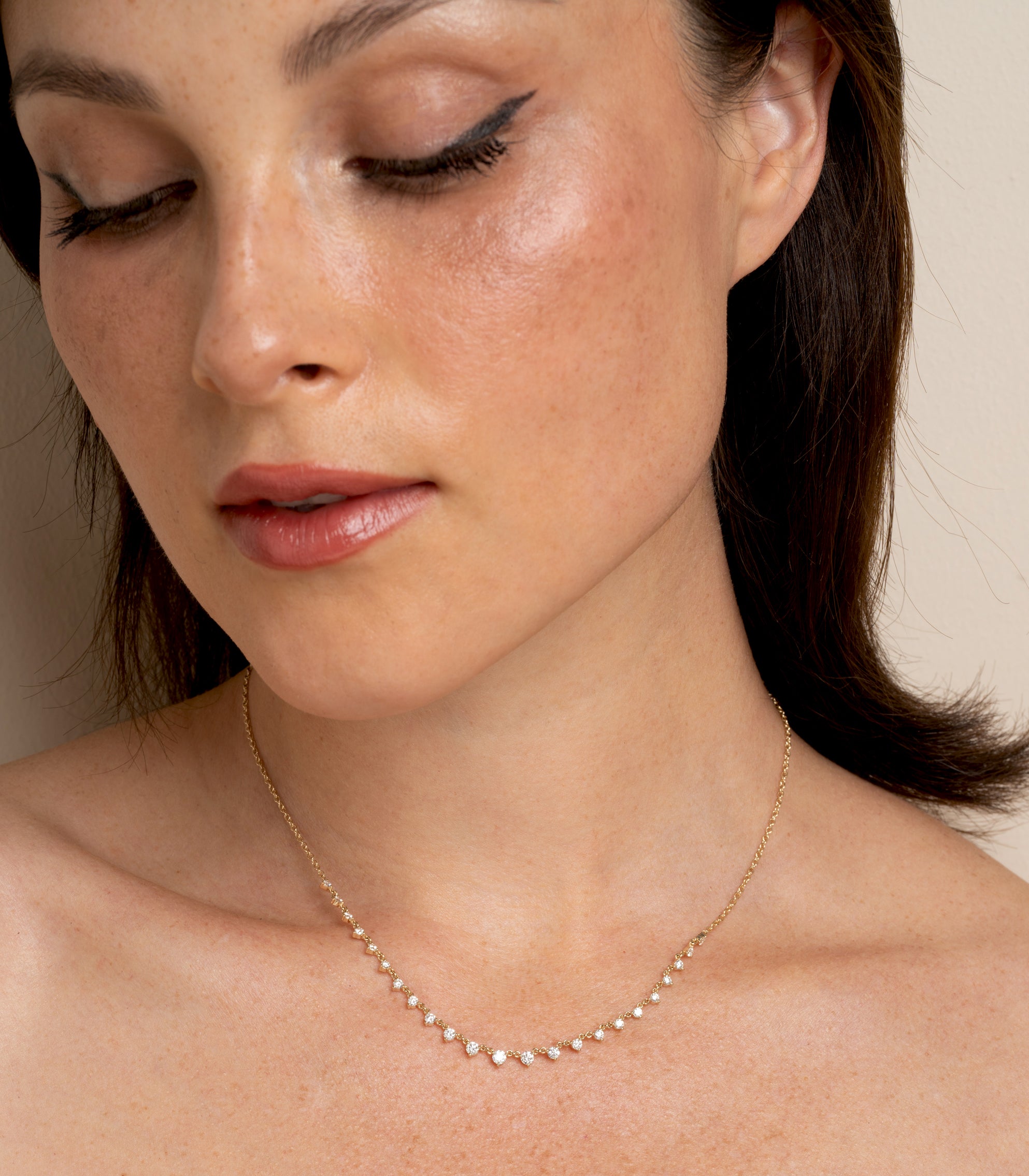 The Larchmont CC-DN9 gold necklace on model, delicate chain with small gemstone-like stones in soft light