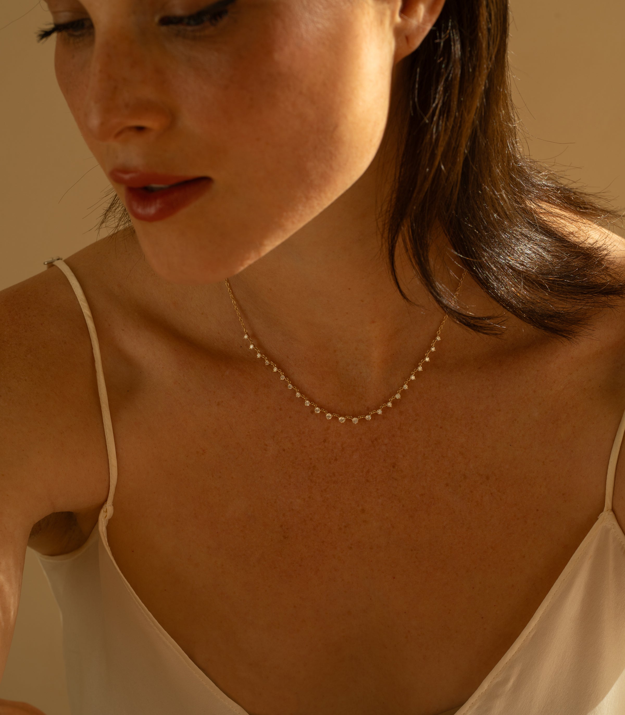 The Larchmont by CC-DN9 gold necklace with small diamond-like stones, softly lit in warm tones
