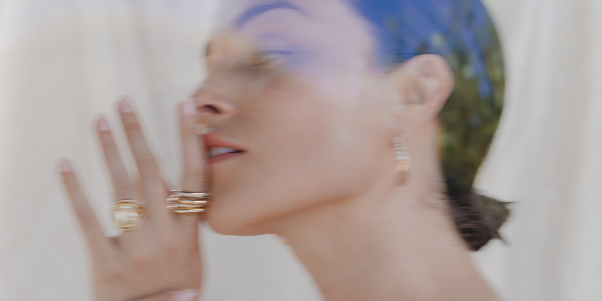 Understated unique engagement ring with prong-set center diamond, shown in a blurred close-up on raised hands