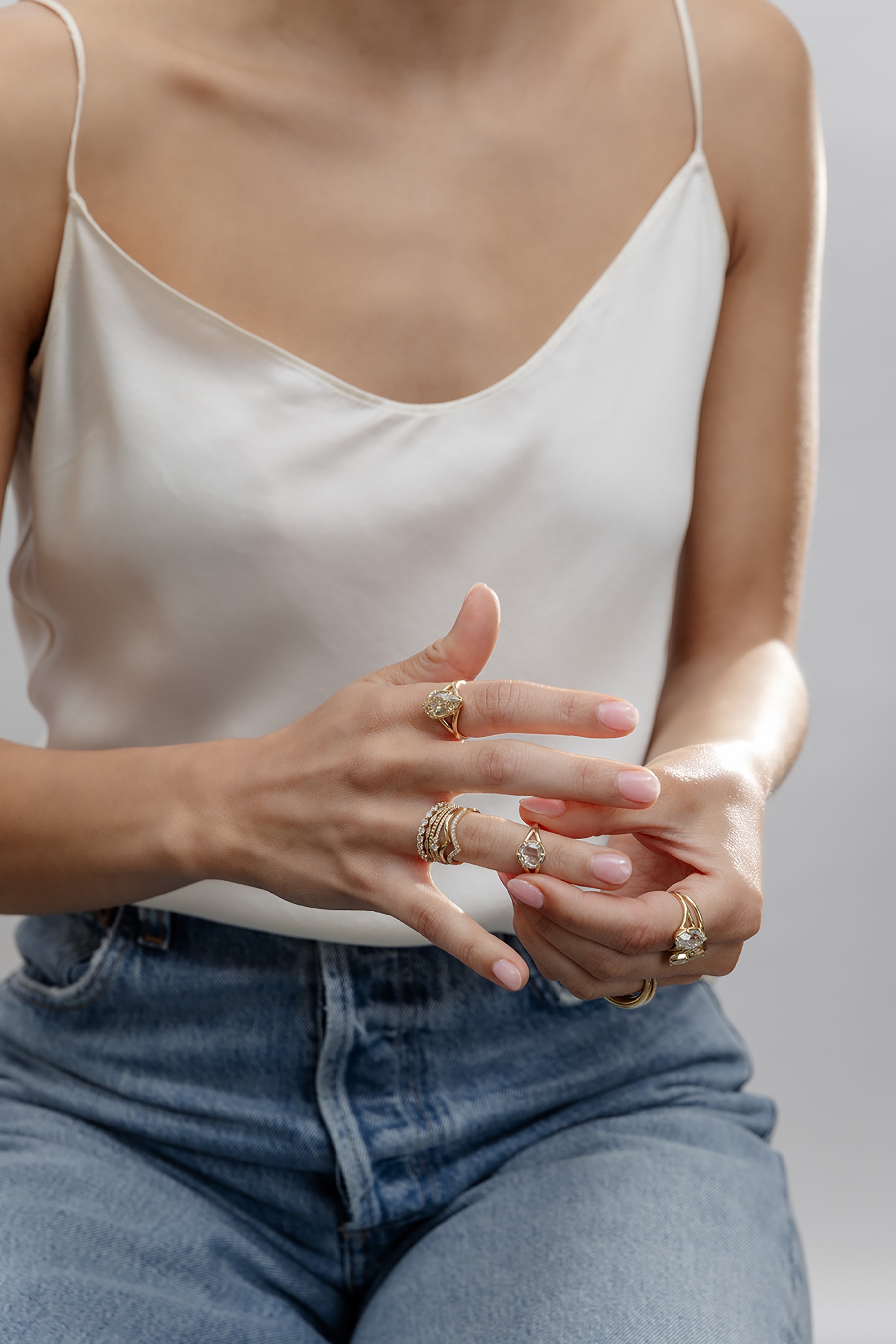 Unique engagement ring on raised hand, with understated gold bands and a sparkling diamond in soft daylight