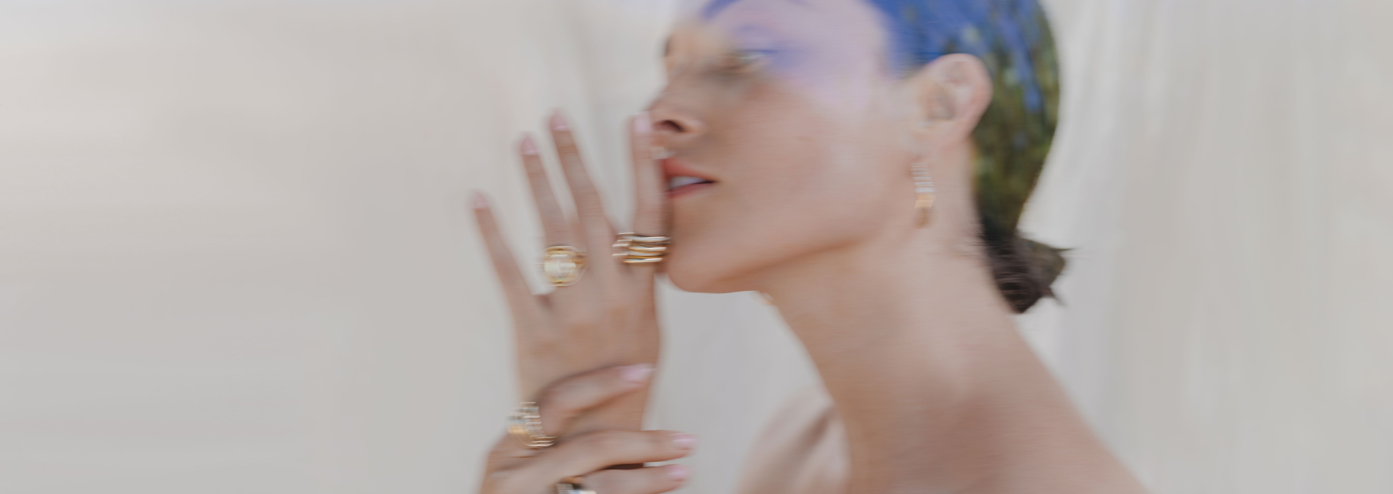 Understated unique engagement ring on a hand with a blurred boho setting in soft light