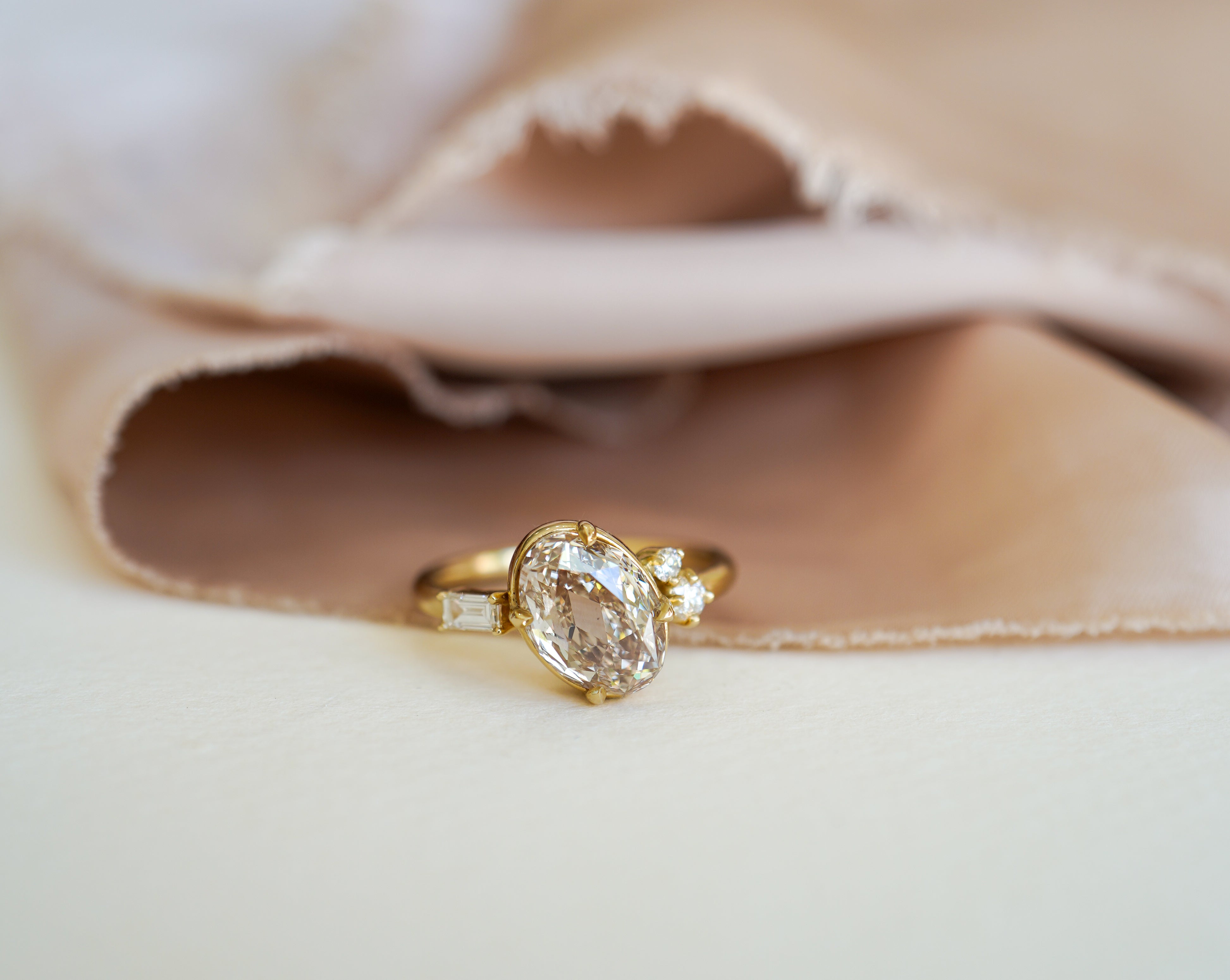 Unique engagement ring with oval center diamond and small side stones on a white surface, understated look