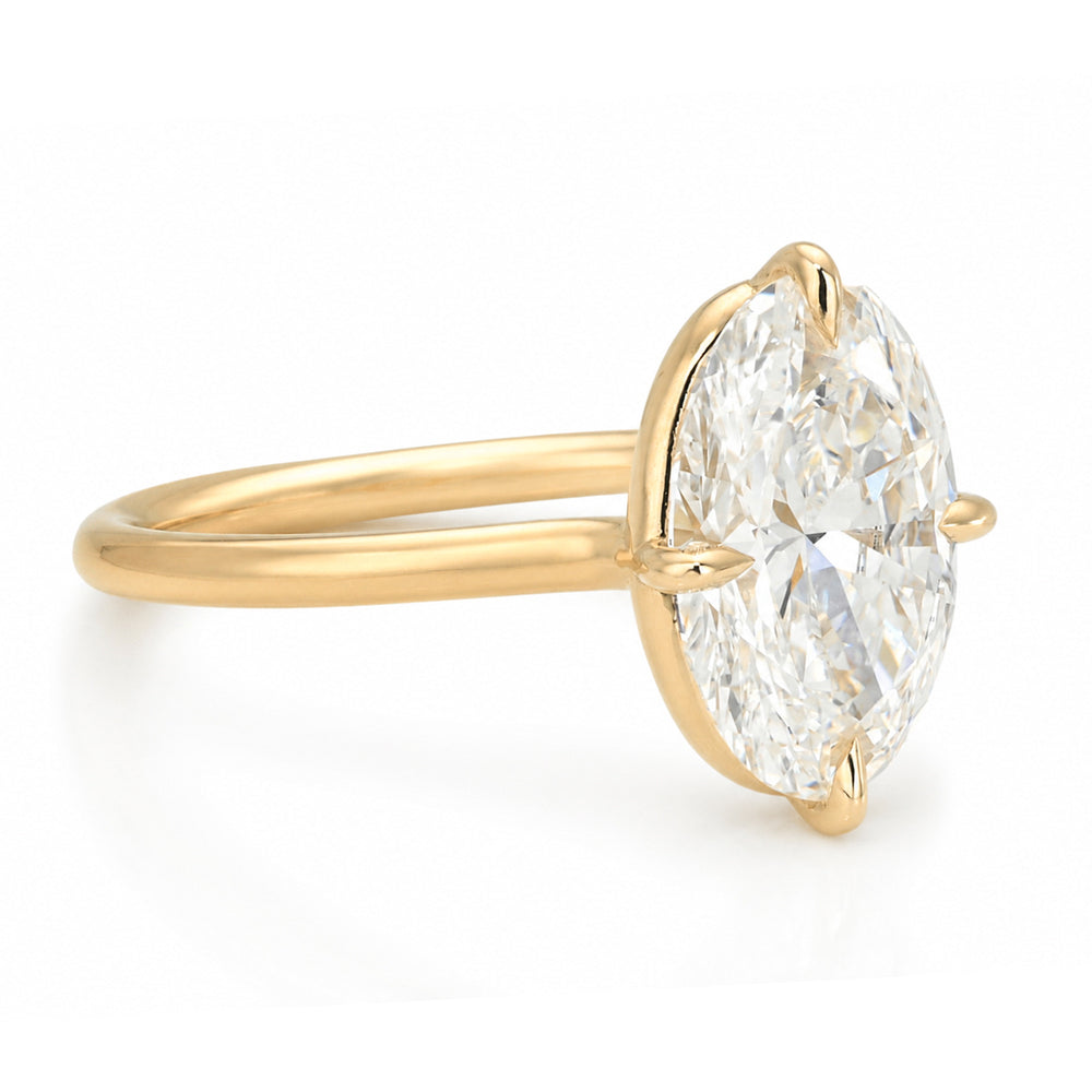 A yellow gold solitaire engagement ring featuring a oval brilliant-cut white diamond in a prong setting, shown on a clean white background.