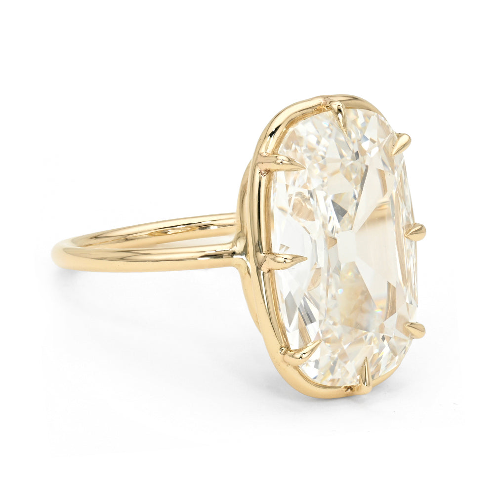 A yellow gold ring featuring a large, elongated cushion old mine cut diamond in a prong setting, shown on a clean white background.