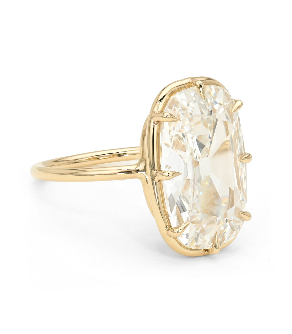 A yellow gold ring featuring a large, elongated cushion old mine cut diamond in a prong setting, shown on a clean white background.