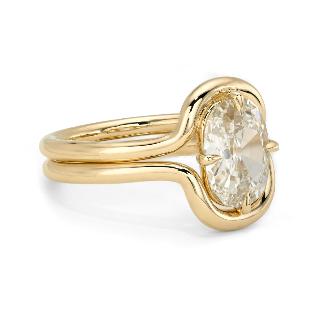 A yellow gold ring with a split shank and a cushion flat old mine cut diamond in a prong setting, shown on a clean white background.