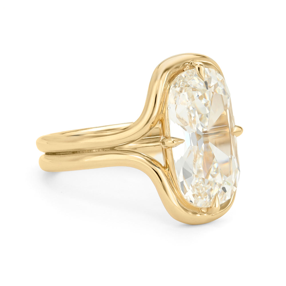A yellow gold ring featuring a large, oval-cut diamond in a prong setting, shown on a clean white background.
