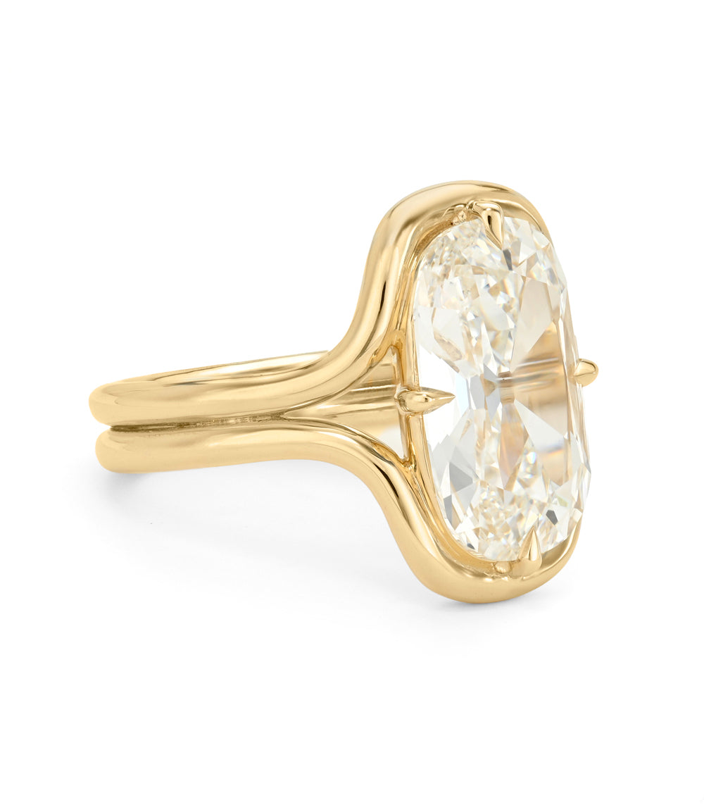 A yellow gold ring featuring a large, oval-cut diamond in a prong setting, shown on a clean white background.