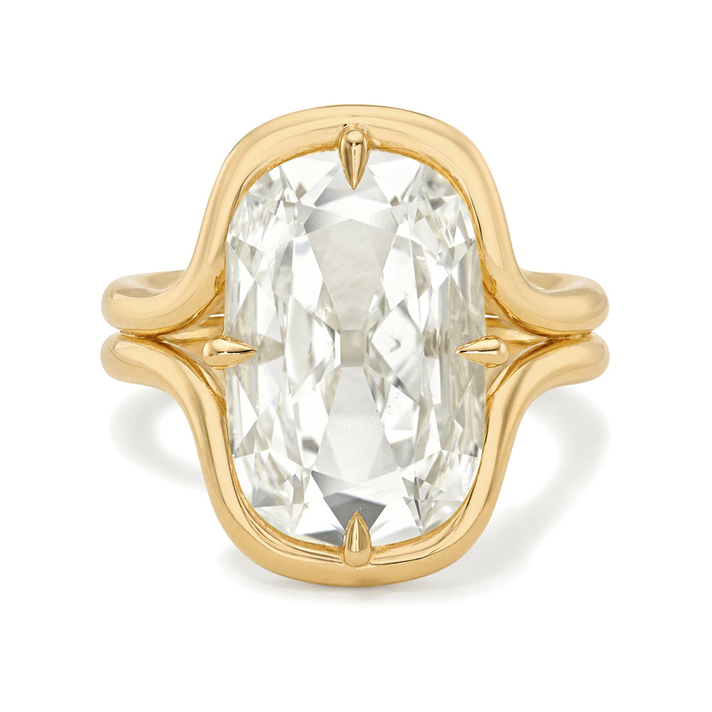 A yellow gold ring featuring a large, cushion-cut clear gemstone in a prong setting, shown against a plain white background.