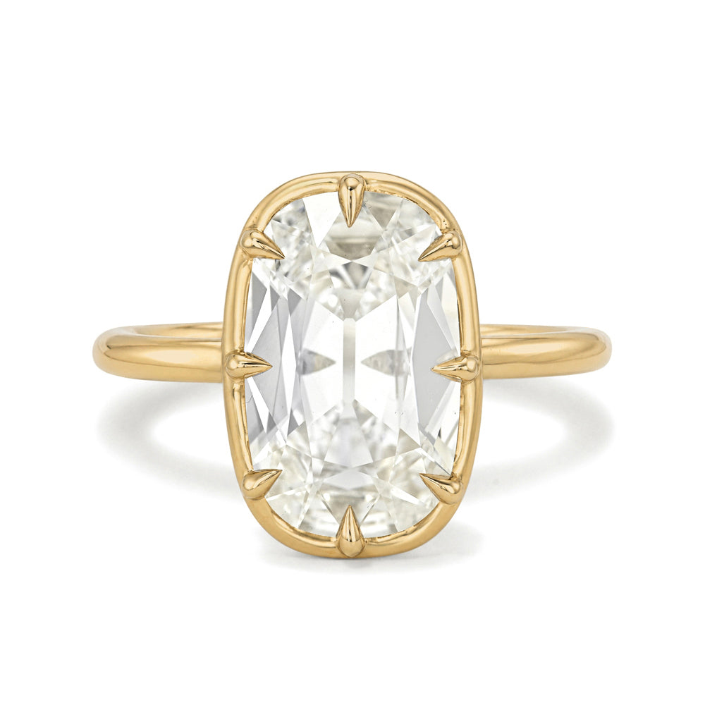 A yellow gold ring featuring a large, cushion-cut clear gemstone in a prong setting, shown against a plain white background.