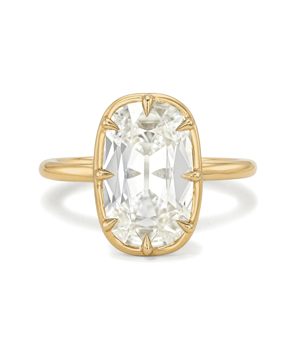 A yellow gold ring featuring a large, cushion-cut clear gemstone in a prong setting, shown against a plain white background.