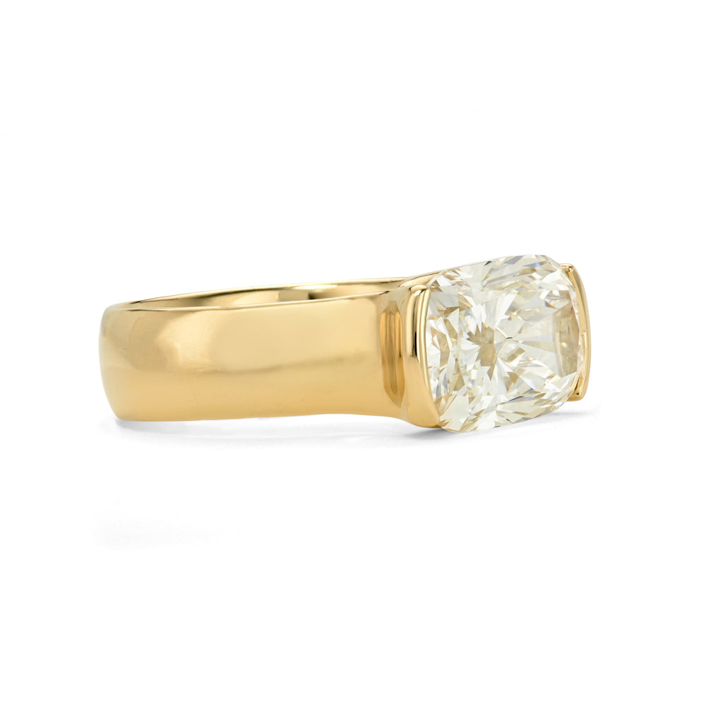 A yellow gold ring featuring a elongated  cushion brilliant-cut diamond in a four-prong setting, shown against a plain white background.