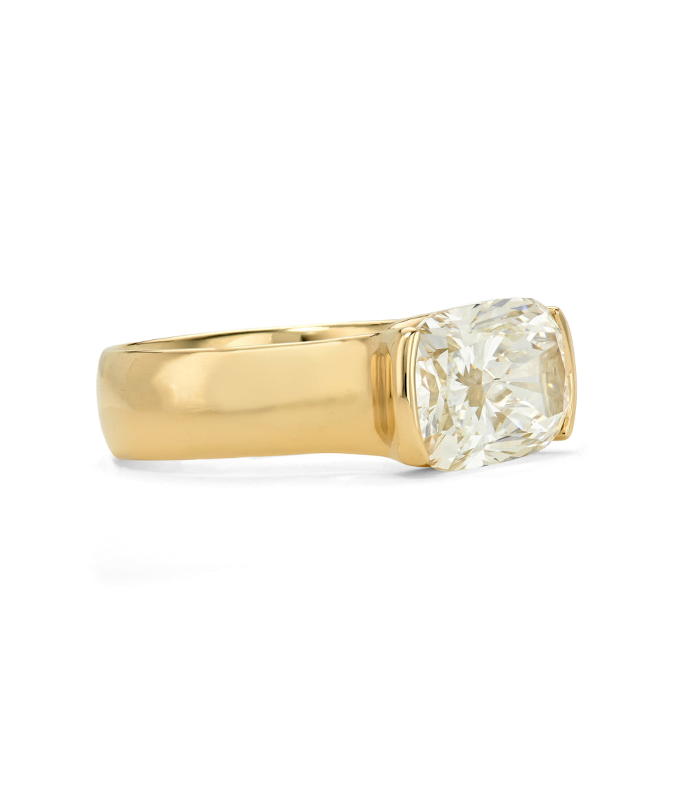 A yellow gold ring featuring a elongated  cushion brilliant-cut diamond in a four-prong setting, shown against a plain white background.