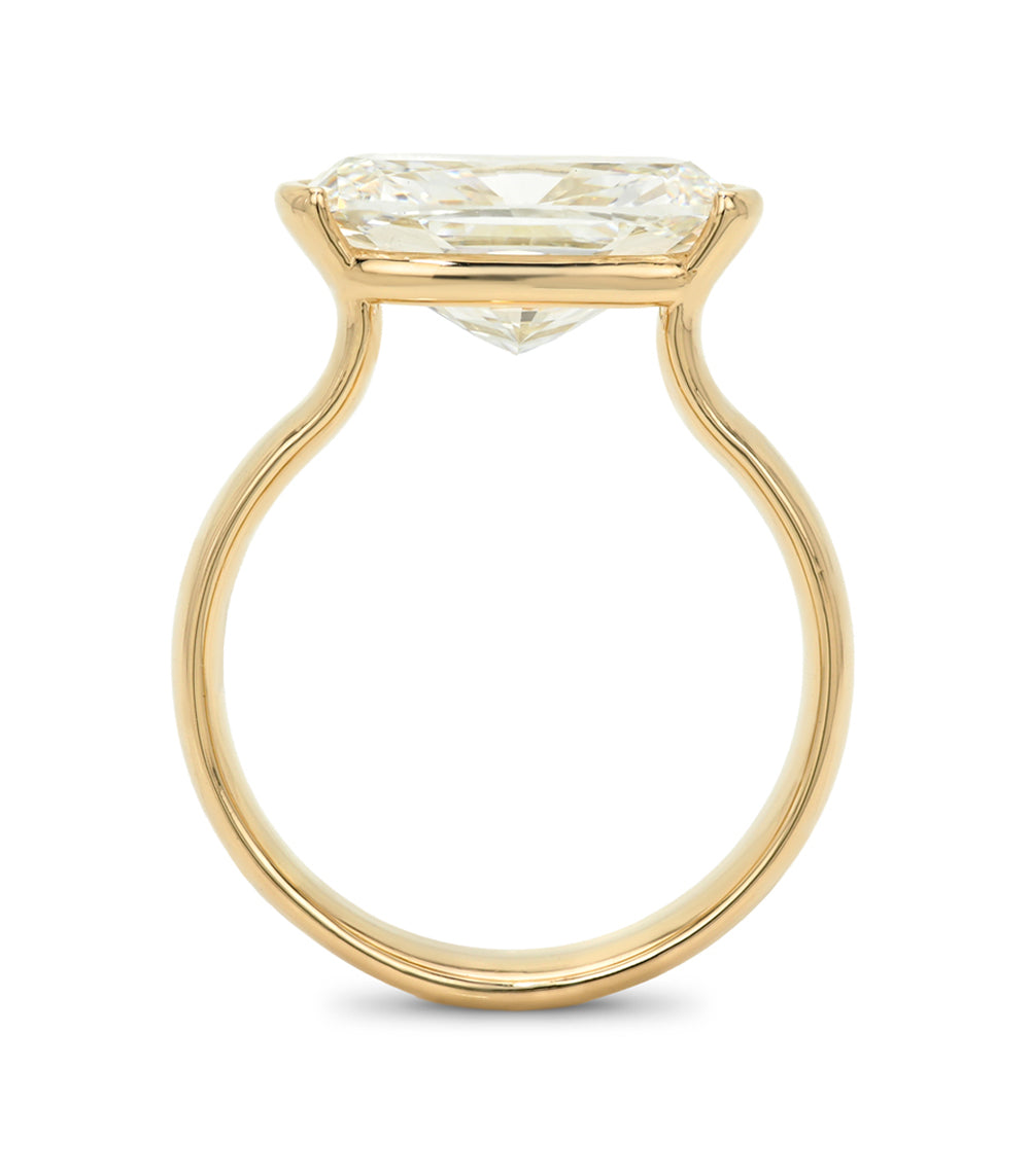 A yellow gold solitaire ring featuring a elongated cushion brilliant cut diamond in a prong setting, shown against a plain white background.