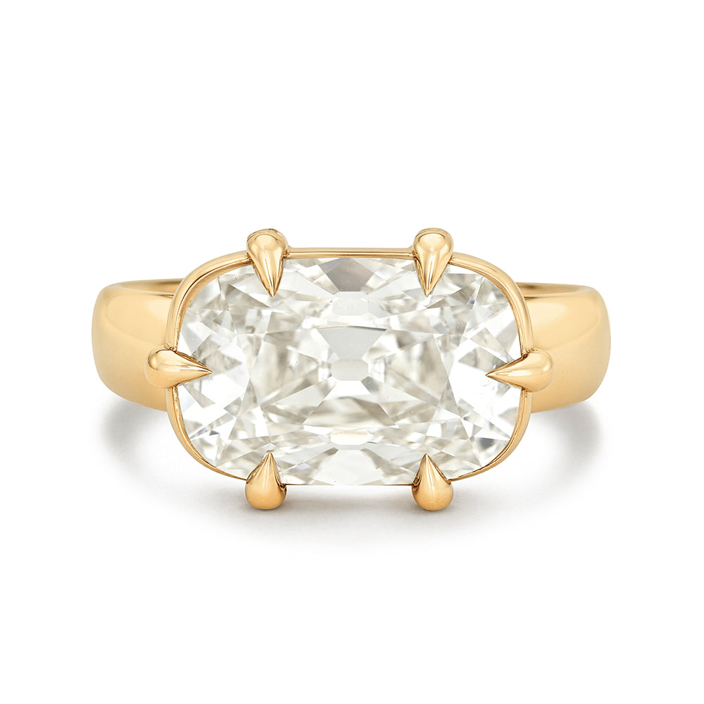 A yellow gold ring featuring a large elongated cushion-cut diamond in a four-prong east west setting, shown against a plain white background.