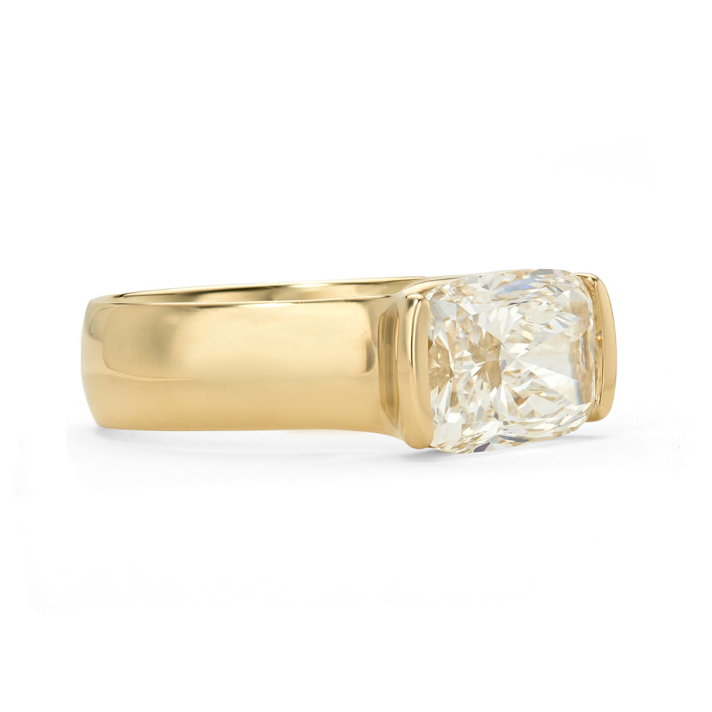 A yellow gold ring featuring a large elongated cushion brilliant-cut diamond in a half bezel setting, shown against a plain white background.