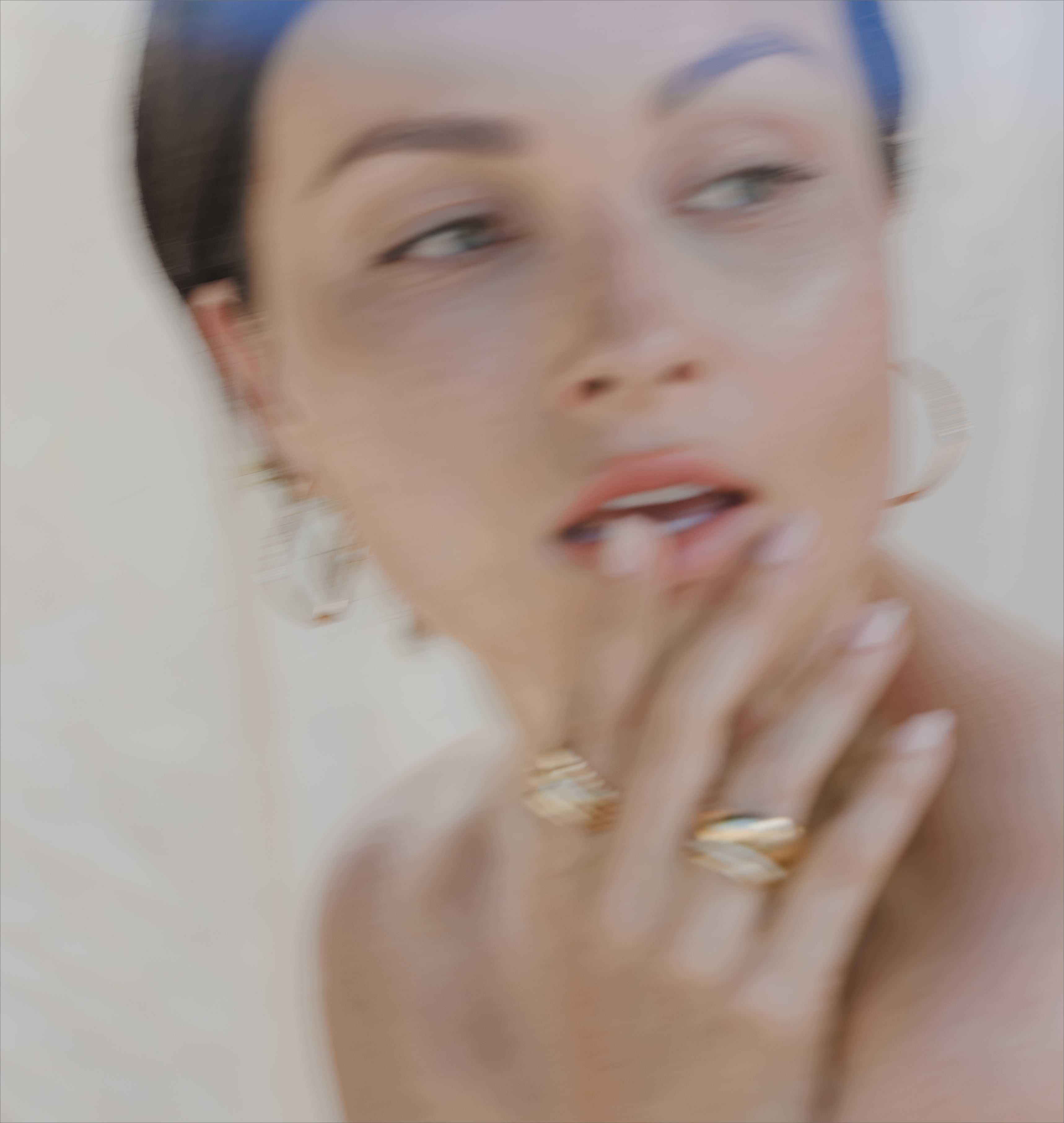 Blurry close-up of a woman’s face with soft makeup, light hair, and a hint of jewelry in warm light