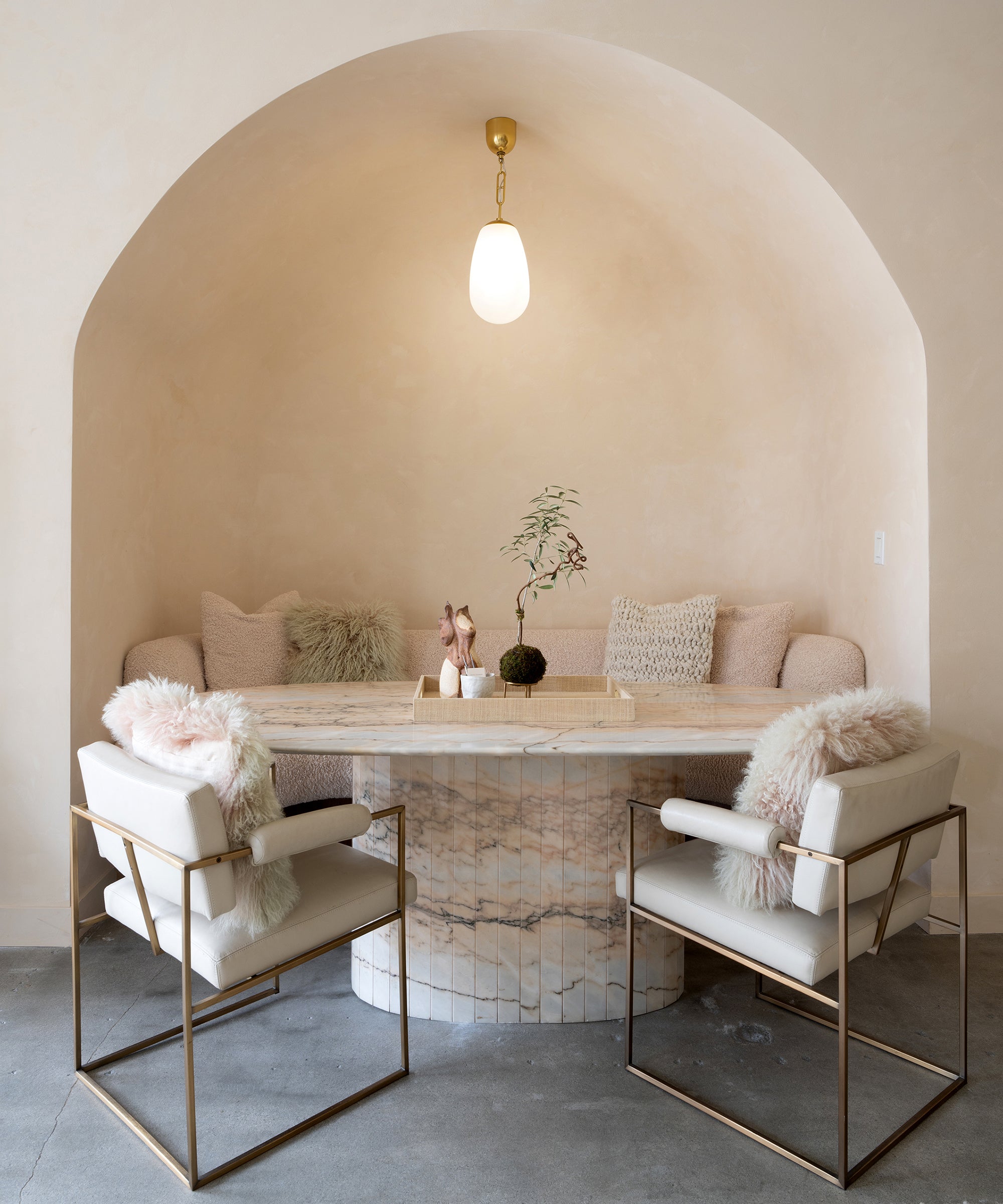 Understated living room lounge with beige tufted chairs, marble table, pendant lamp, and soft decor.