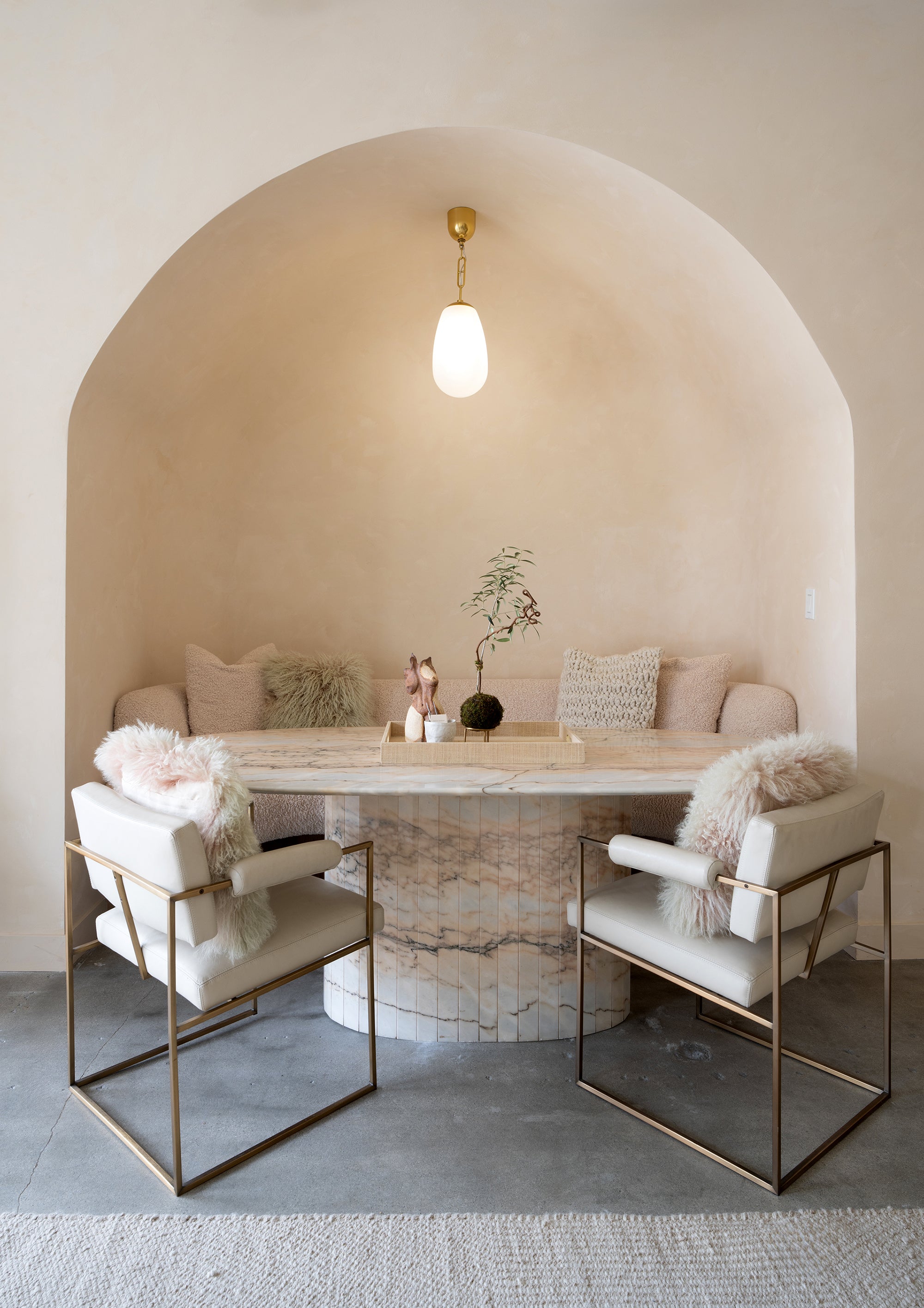 Understated lounge area with two cushioned chairs, a wood table, and warm pendant light