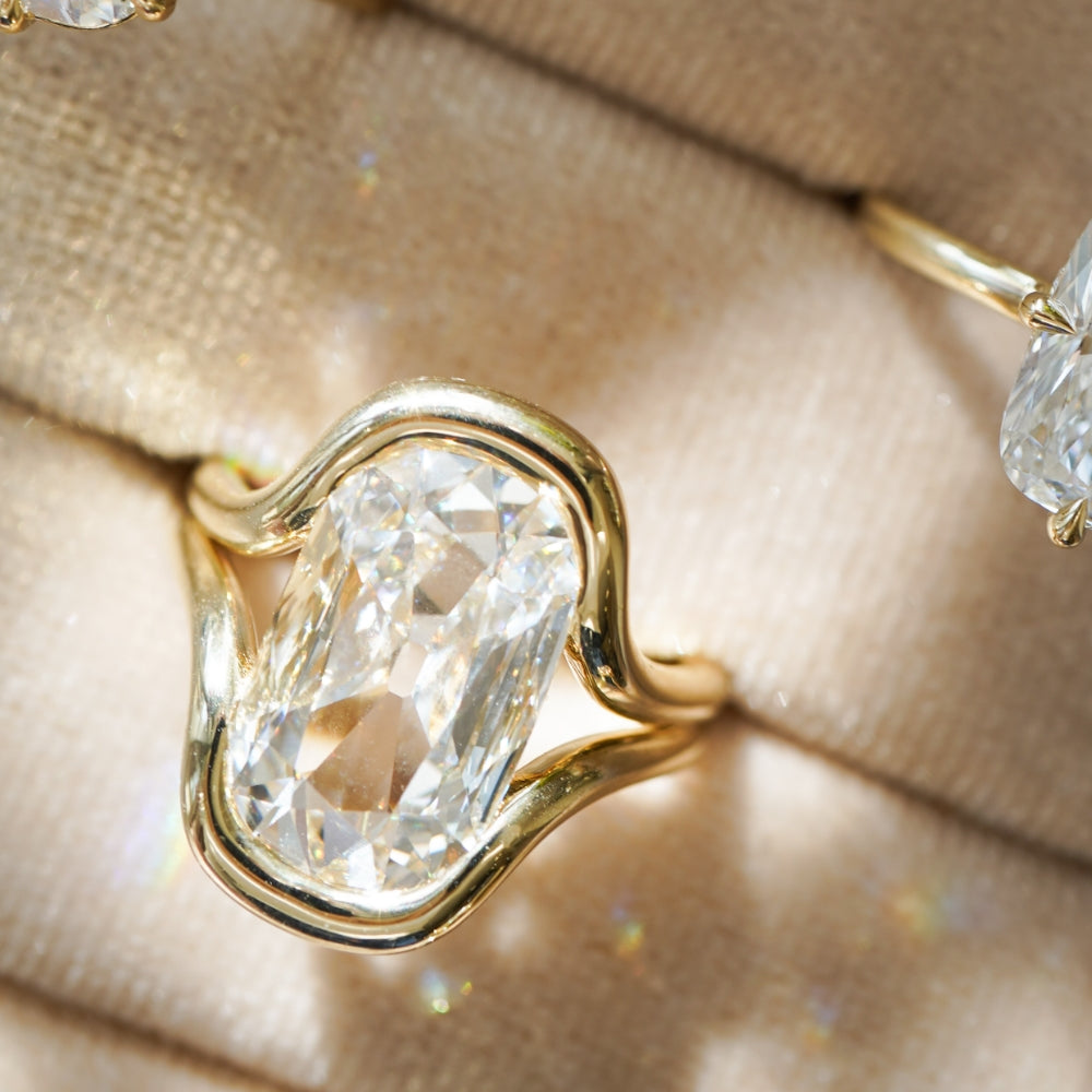 Onda by Sofia Kaman unique engagement ring in warm gold with a clear cushion-cut diamond centerpiece
