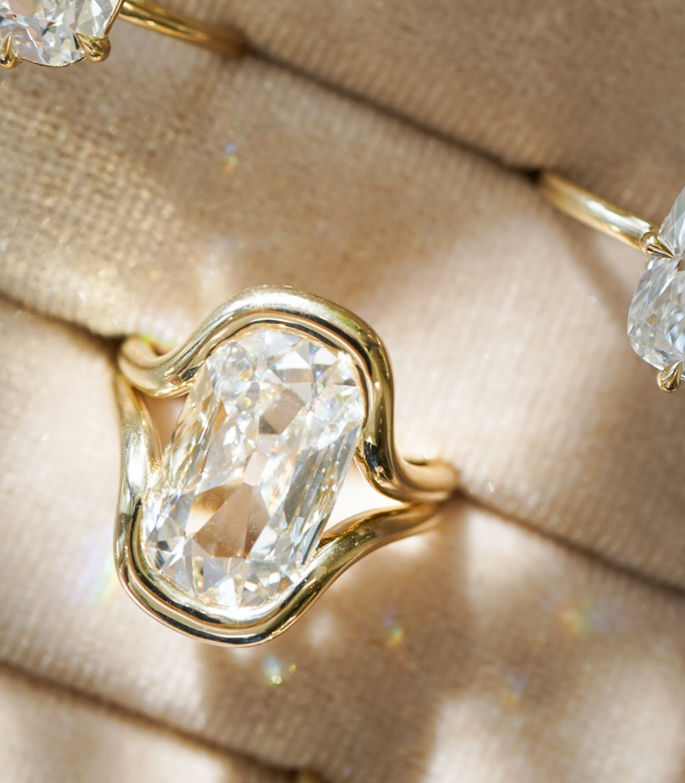 Onda by Sofia Kaman unique engagement ring in warm gold with a clear cushion-cut diamond centerpiece
