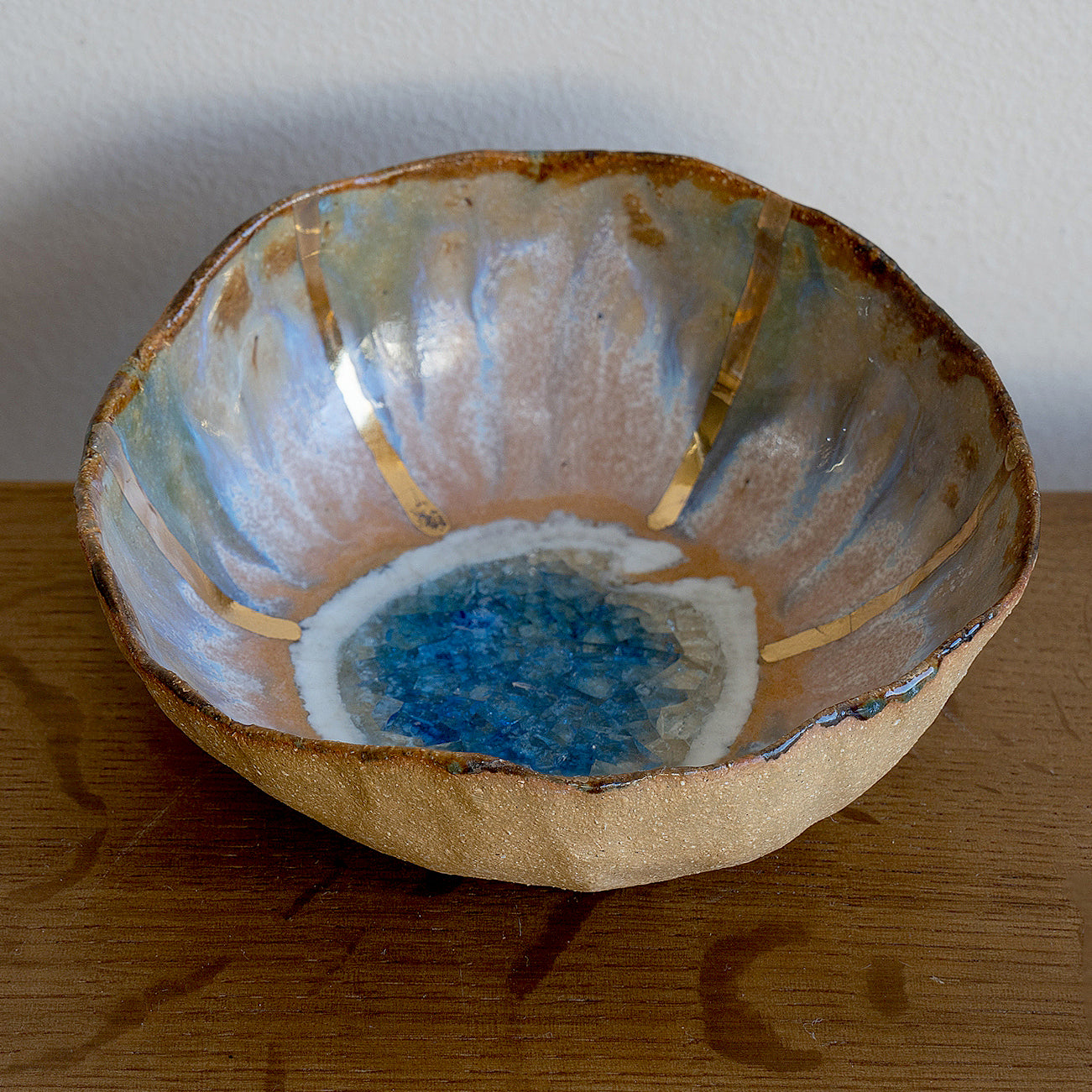 Blue Lagoon Ring Dish G-006 ring dish with blue ocean resin center and speckled gold rim on wood