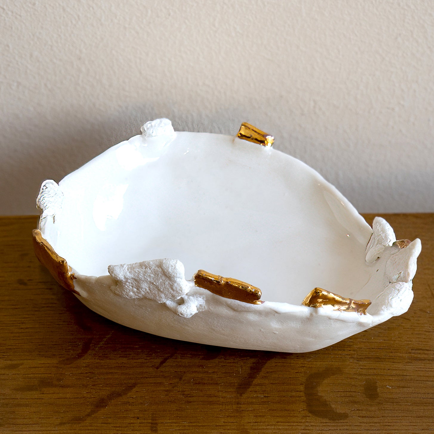 Halo Ring Dish G-009 white ring dish with gold accents for holding rings on a wooden table