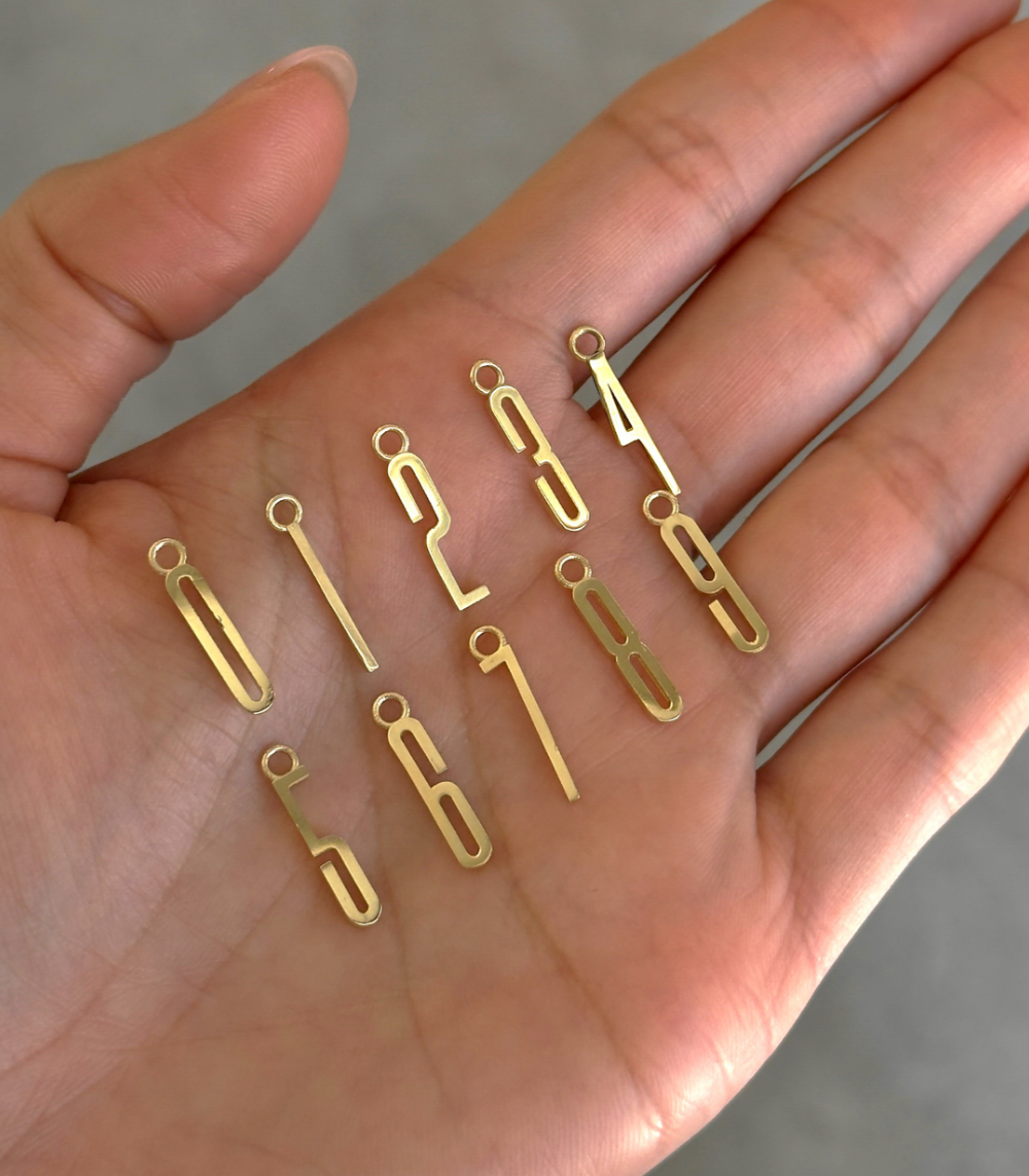 ID NECKLACE NO.1 by ID-N1 gold letter pendant necklace shown on hand with soft natural light