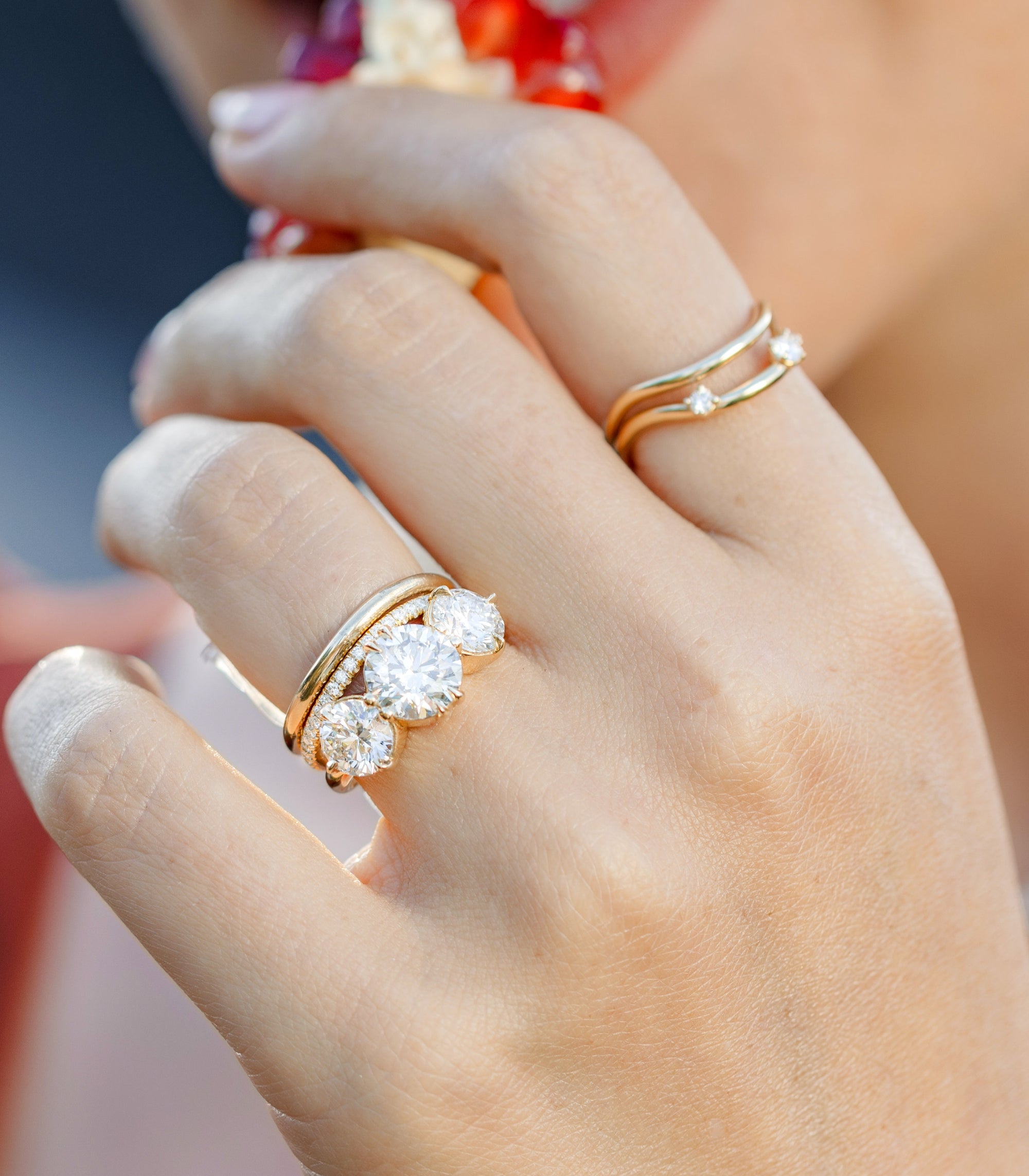 Unique engagement ring on hands, gold band with round diamonds in a 3 stone engagement ring style