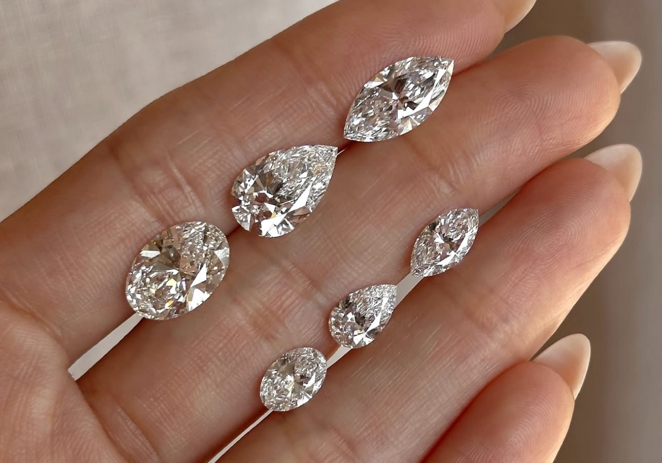 Unique engagement ring set of understated asymmetrical engagement ring with pear-cut diamonds on open palm