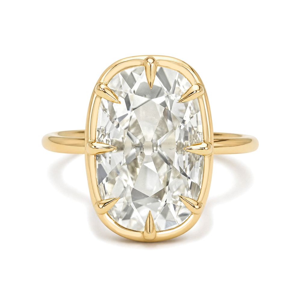 Gold ring with a large flat elongated cushion old mine cut diamond on a white background