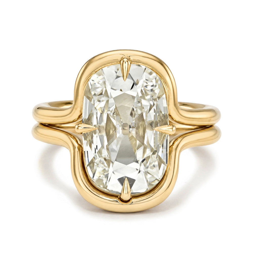 A yellow gold ring featuring a large, oval-cut clear gemstone in a decorative setting with a split shank design, shown on a plain white background.