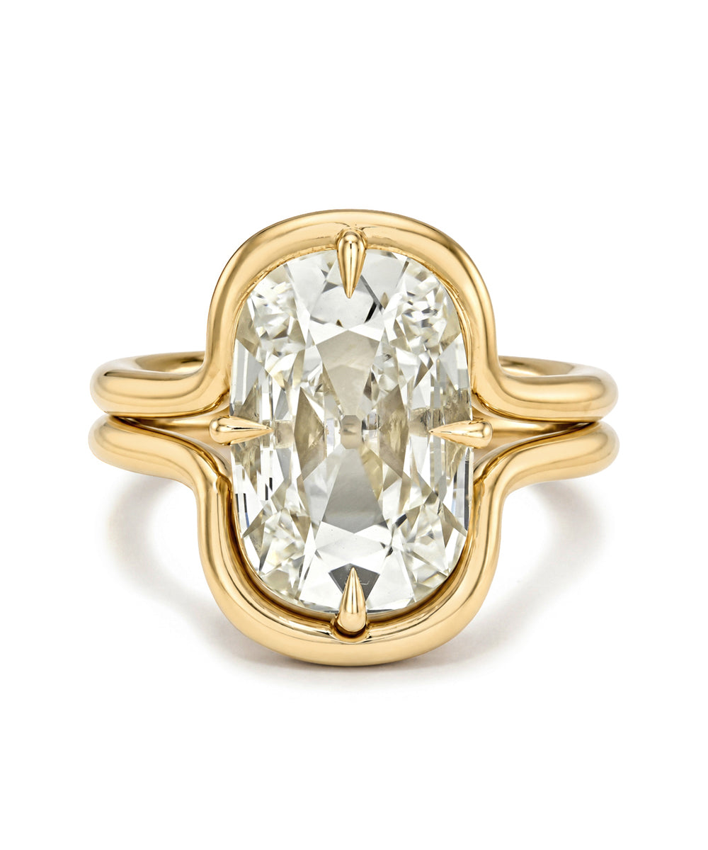 A yellow gold ring featuring a large, oval-cut clear gemstone in a decorative setting with a split shank design, shown on a plain white background.
