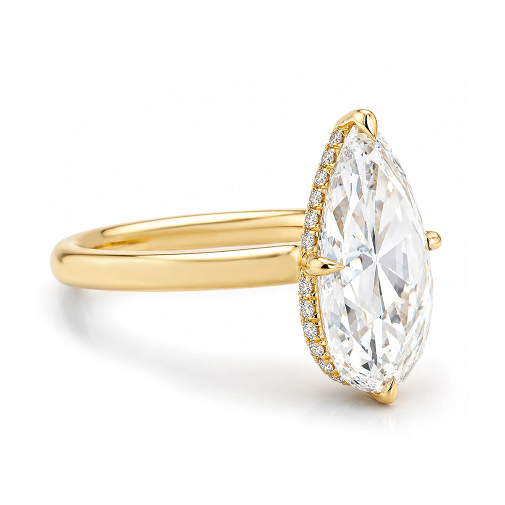 A yellow gold ring featuring a large marquise-cut clear gemstone in a prong setting, accented by a halo of small round diamonds along the side, set against a clean white background.