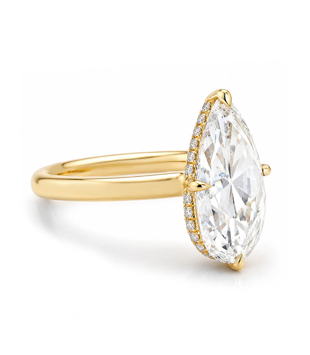 A yellow gold ring featuring a large marquise-cut clear gemstone in a prong setting, accented by a halo of small round diamonds along the side, set against a clean white background.