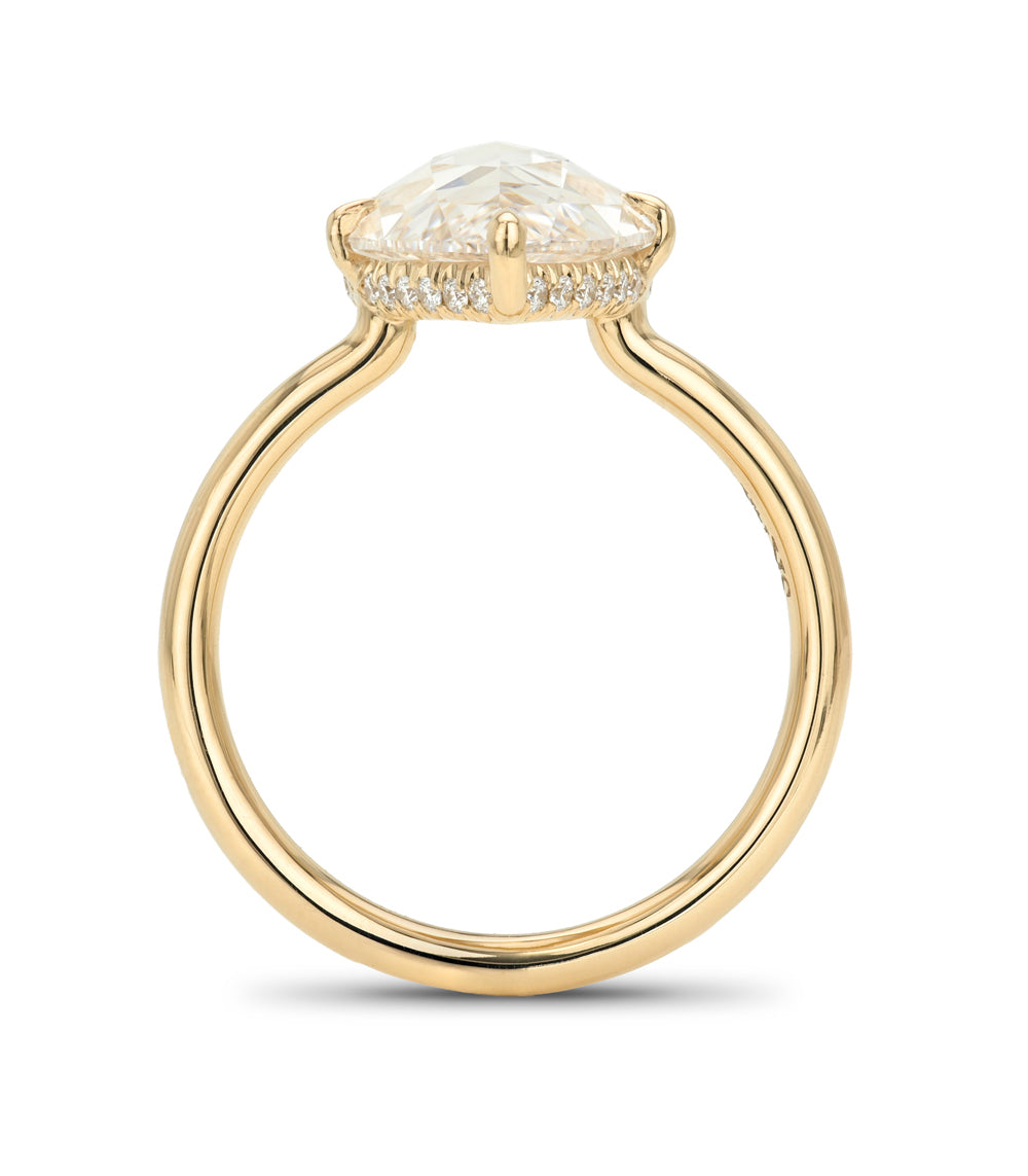 A yellow gold ring featuring a large cushion-cut clear gemstone in a prong setting, accented by small pavé diamonds along the band, shown against a plain white background.