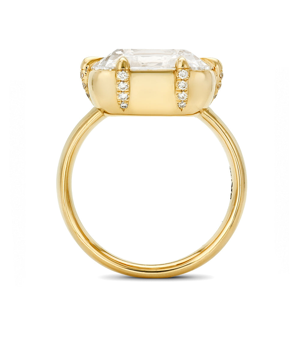 A yellow gold ring featuring a large elongated cushion diamond in a prong setting, accented with small pavé diamonds on the shoulders, shown on a plain white background.