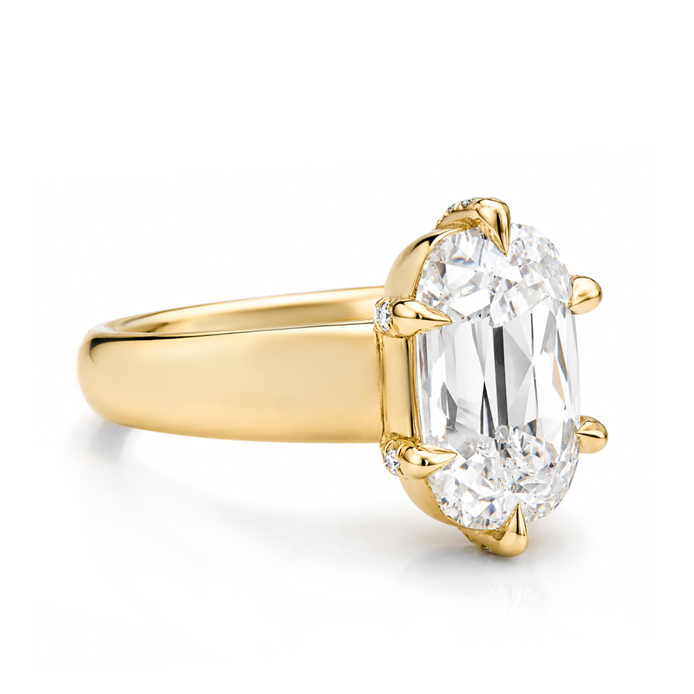 A yellow gold ring featuring a large elongated old mine-cut diamond in a prong setting, shown on a clean white background.